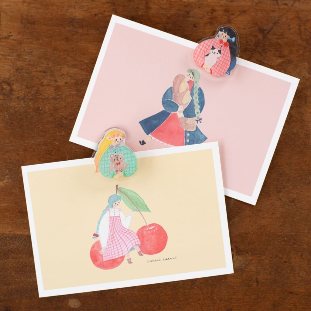 ねことクマが女の子に優しく抱かれているイラストが描かれた「リバーシブルアクリルクリップ」は、cotori cotoriさんのデザイン。
