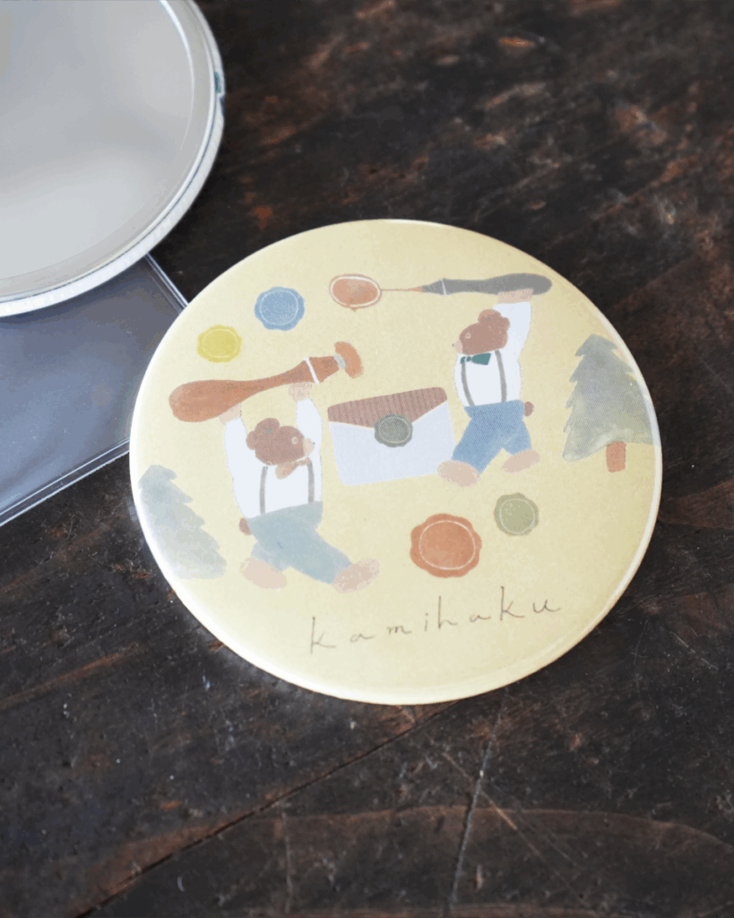 「紙博缶ミラー」携帯しやすい手のひらサイズで、小さめのバッグやポーチにも入ります。カバー付きなのもポイント！（600円／Illustration：トビマツショウイチロウ）