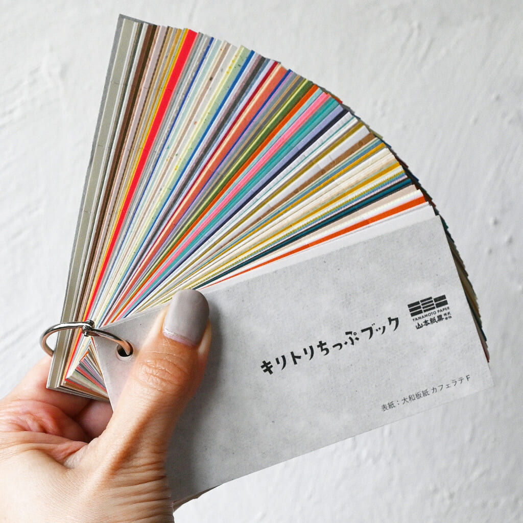 「キリトリちっぷブック」山本紙業に【紙の島】が登場します！　すべての紙にミシン加工を施しているのでピリピリ切り取ってコラージュなどにご使用ください。紙をせっせと運ぶミニチュアトラックがお出迎えしますよ。
