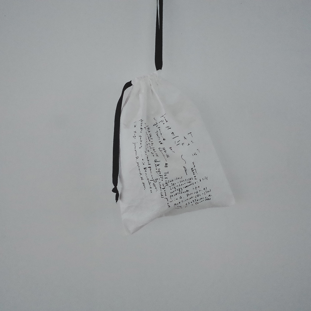 「タイベックの巾着」紙のような質感の素材を使って、細かい文字をプリントした巾着です。使っているとだんだん柔らかくなります。