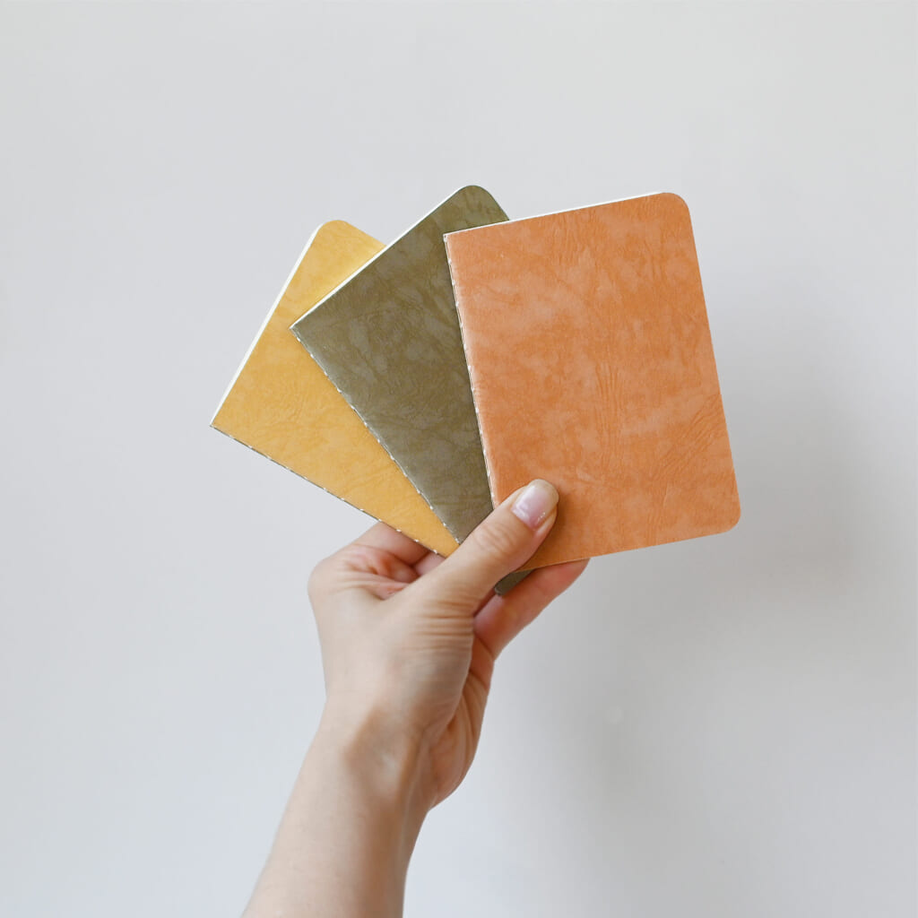 「RO-BIKINOTE TextureSeries」蝋引き加工を施すことで紙そのものが持つ風合いをさらに際立たせる表現にチャレンジした新しいシリーズ 蝋引き加工を経てより深みのある表情へと変化し、蝋の含侵量の違いによって現れる透明感のコントラストも楽しめます。