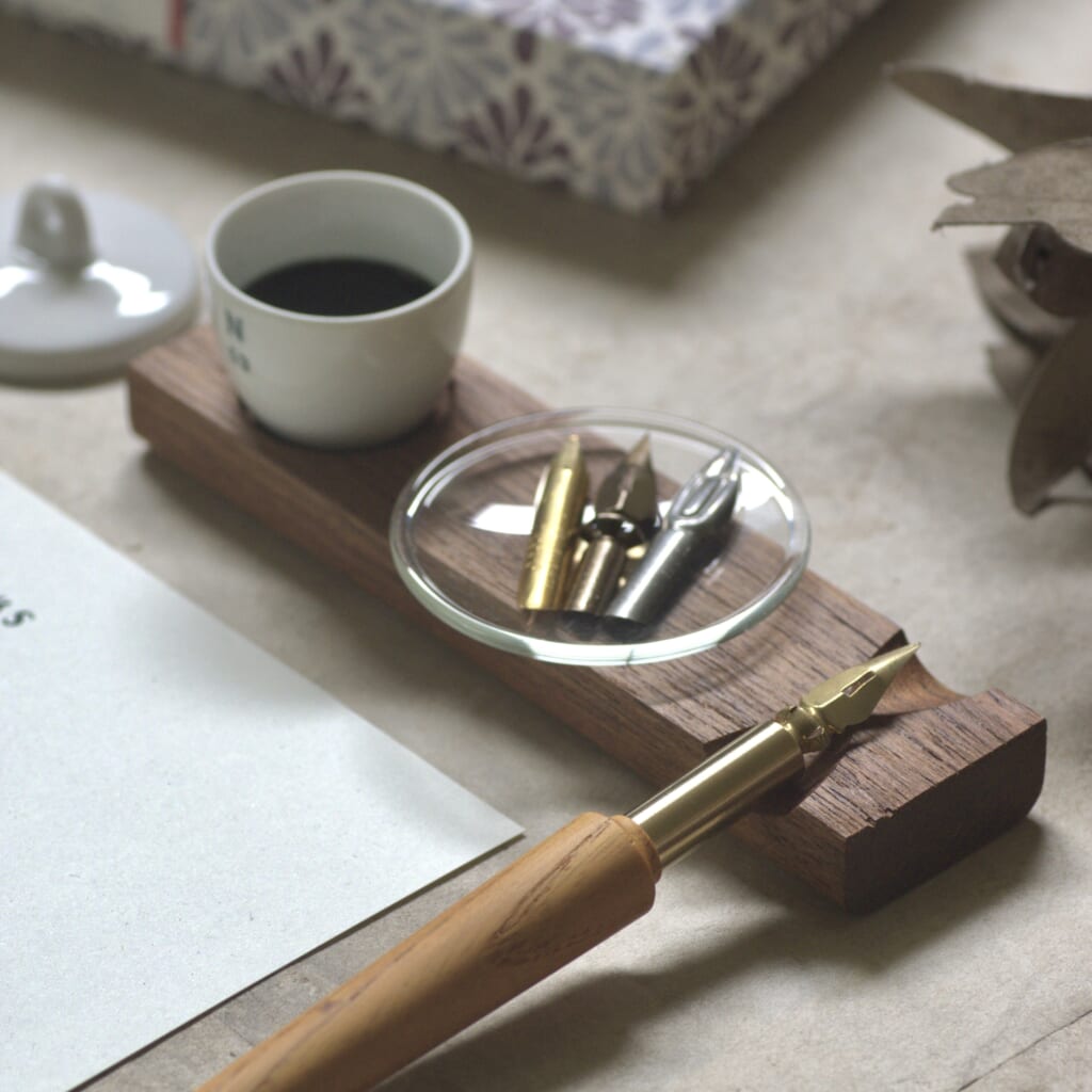 「坩堝（るつぼ）と時計皿のペンレスト」口が広くいろいろな用途で使える「磁製の坩堝」と、トレイになる「時計皿」、そして「ペンレスト」。これら3つの役割をひとつに組み合わせた作品です。この他にも「ガラス壺とペンレスト」など、さまざまな組み合わせをご用意しています。