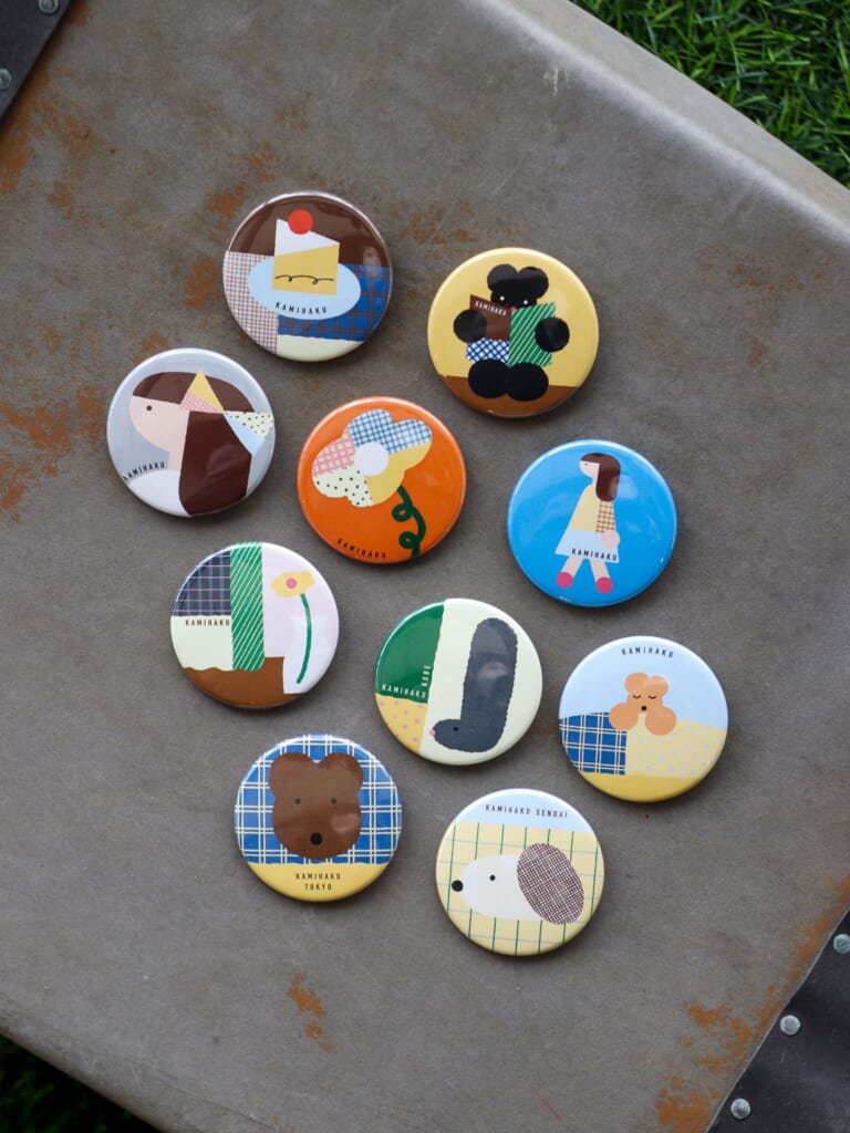 「缶バッジ（全8種）」（300円／Illustration：しまむらひかり）