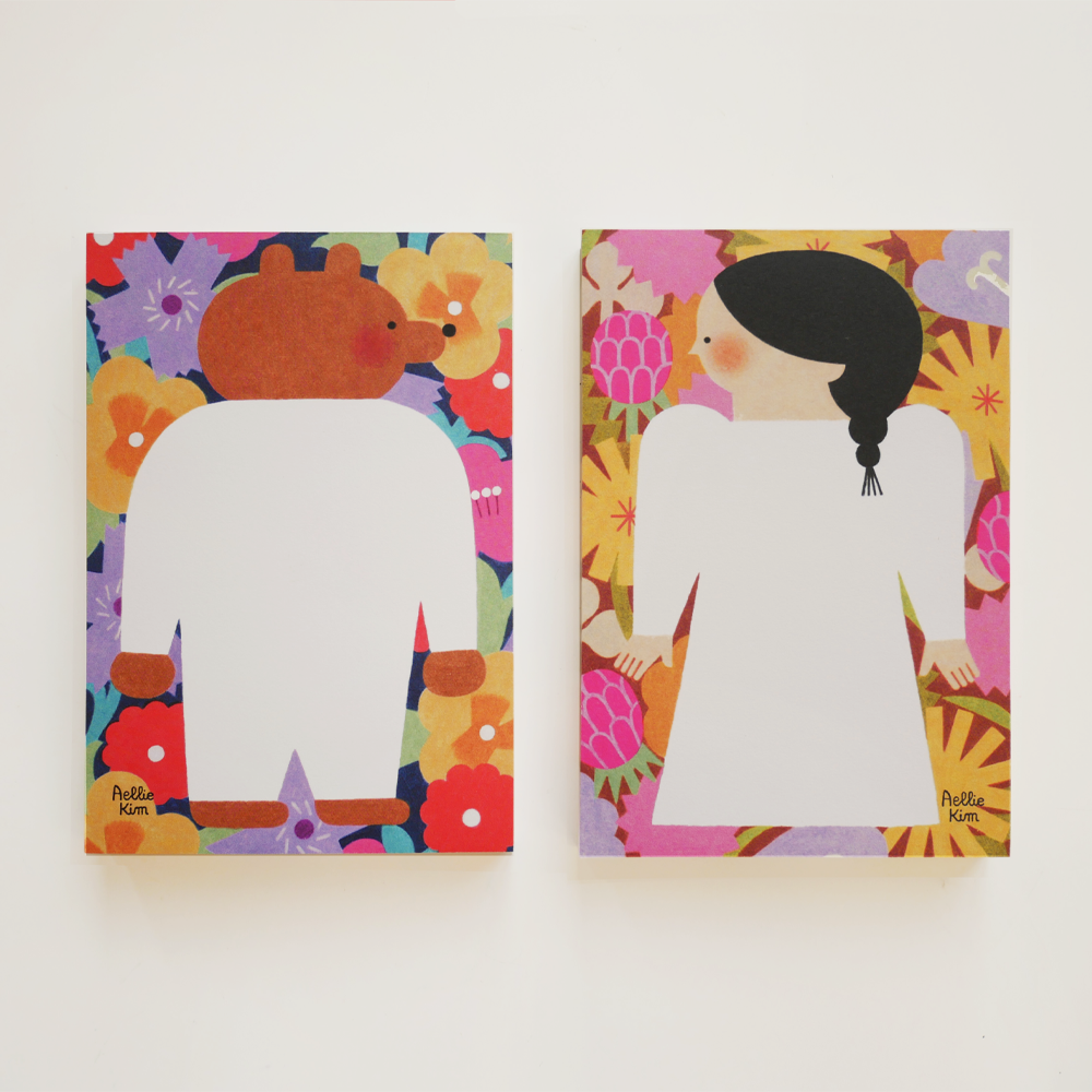 「メモパッド」春の花々に囲まれたクマと、秋の植物に囲まれた少女を描いた、2種類のメモパッドです。